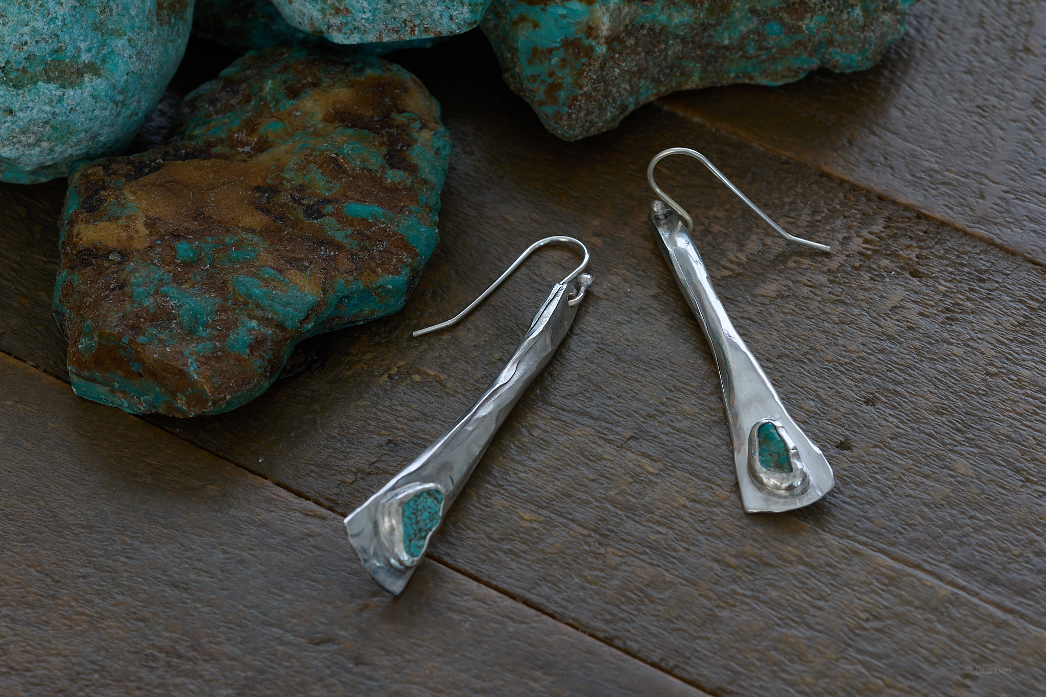 Turquoise earrings on wood tabletop.