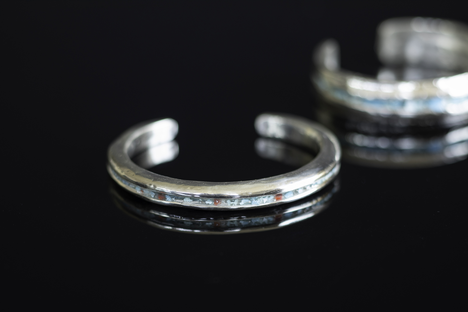 Cuff on black tabletop with turquoise inlay.