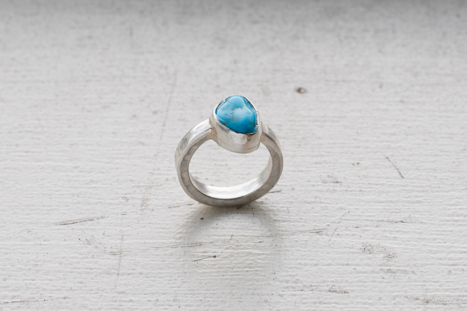 Turquoise ring on weathered off white background.